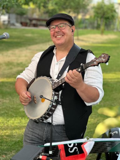 Mann mit Banjo und Hut spielt Musik im Freien.